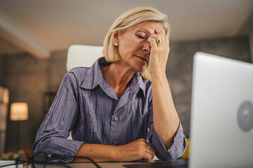 Mature senior woman work from home and have eyestrain pain