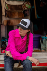 Barrel racer Cowgirl in bright pink shirt and hat in horse trailer
