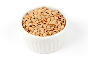 Pile of brown raw dry lentils in ceramic bowl isolated on white background