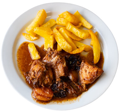 Pollo rustido in Catalan - baked chicken flavored with oregano, white wine, sweet wine, grapes, prunes. Served with French fries. Isolated over white background
