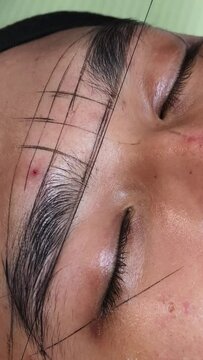 Using inked threads to make guide lines around the eyebrows of a male patient to get te exact measurements for microblading procedure.