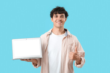 Male programmer with blank laptop showing thumb-up on blue background