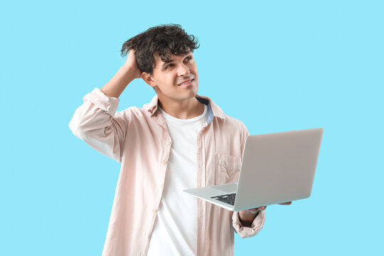Thoughtful male programmer with laptop on blue background