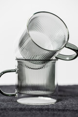 Zwei Glastassen in transparent grau vor einem weißen Hintergrund.