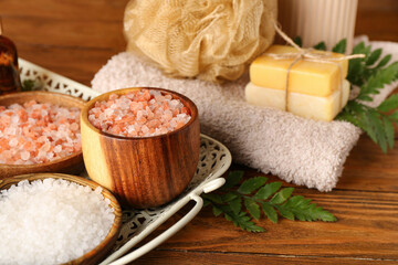 Composition with sea salt and spa accessories on wooden table, closeup