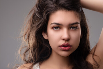 Naklejka premium Beautiful latin woman touching her hair on gray background