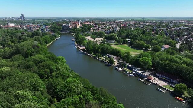 Flying away from the city center of Bernburg along the river Saale. Sports boats are moored on the banks. Sunny day in summer. A city worth seeing in Saxony-Anhalt.