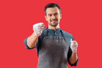 Portrait of male jeweler with earring and magnifier on red background
