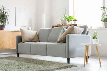 Grey sofa with cushions in interior of light living room