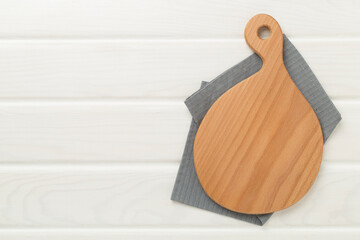 Cutting board with napkin on wooden background, top view