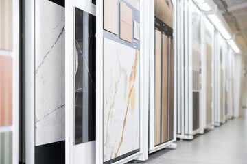 Range of natural and technical stone tile samples in different colors and textures displayed on sliding panels in showroom, showcasing design options for interiors