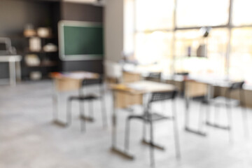 Blurred view of empty classroom with desks and chalkboard