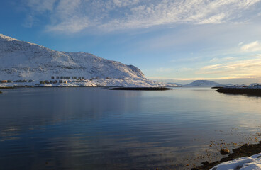 Fototapeta premium Just sitting and watching this view of blue water and skies and white snowy mountains all day, letting the day pass by.