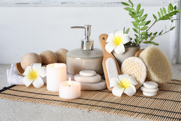 Glowing aroma candles with spa supplies and cosmetics on light background
