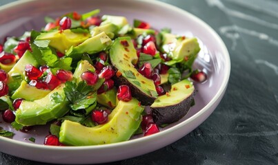 Avocado and pomegranate salad on a pastel purple plate