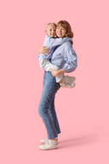 Happy mother and her little son hugging on pink background