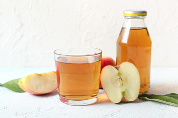 Glass and bottle of fresh apple juice on light blue table