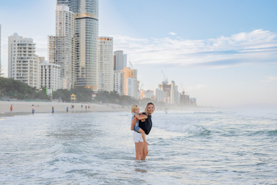 Mother giving son piggy back ride on Main Beach, Surfers Paradise on the Gold Coast