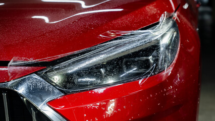 Close-up of a red car headlight with vinyl wrap.  © Михаил Решетников