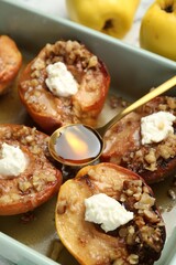 Tasty baked quinces with nuts, honey and cream cheese in dish, closeup