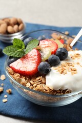 Tasty granola with berries, yogurt and mint on grey table, closeup