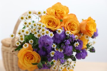 Wicker basket with beautiful flowers on white background, closeup