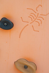 Closeup of child climbing wall with hand grips and stick figure scorpion detail