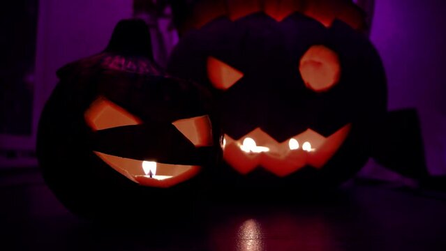 Horizontal Full HD video. Jack Lantern. Pumpkin with carved evil face, cheerful muzzle, burning candle on windowsill. Violet sparkle, purple lights on background. Concept of Halloween, holiday, fun