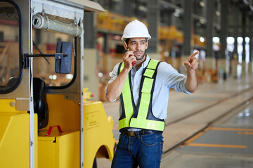 Engineer or worker talking on walkie talkie with a car in the factory