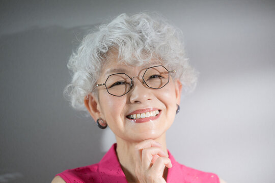 Close-up of an elderly woman with gray hair looking at the camera as she thinks with her hand on her chin