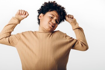 Joyful african american boy celebrating with arms raised enthusiastically against a clean white background, embracing pure happiness