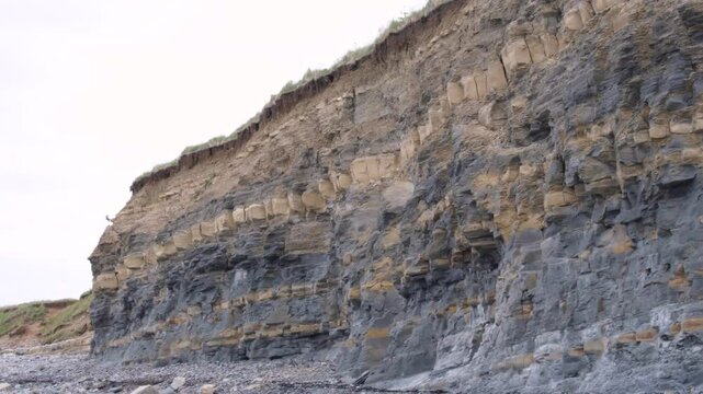 Kilve Beach limestone cliffs of oil-rich shale and layers of yellow, brown blue lias on the Jurassic Coast in England UK