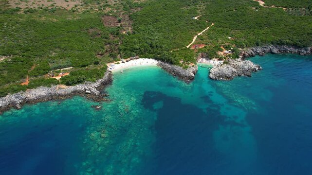 Secluded White Sand Beach Hidden Among Rocks and Green Hillsides with Emerald Waters of the Ionian Sea in Albanian Coastline