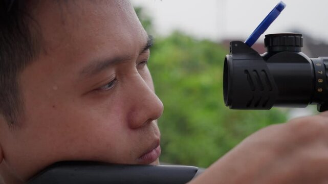 Asian sniper with scoped pcp air rifle shooting in slow motion