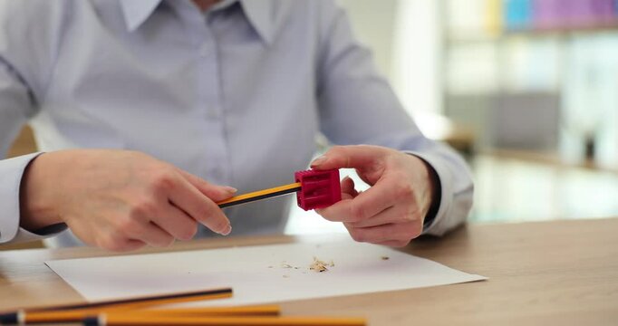 Office worker inserts pencil into opening of sharpener