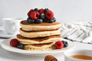 Pancakes with raspberries and blueberries on a light background for breakfast