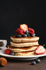 Homemade pancakes with berries on a dark background