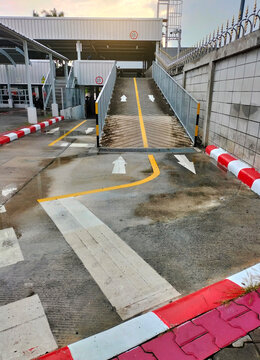 White arrows indicate directions outside an industrial building. Yellow painted motorbike parking lot between parallel yellow lines on abstract cement background