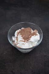 Ice cream with grated chocolate in a glass plate on dark background