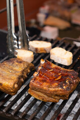 Marinated pork ribs are cooked on the coals of a barbecue