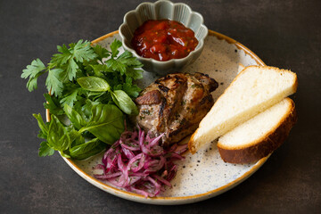 Plate of fried pork meat with bread, sauce and greens