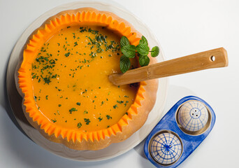 A large pumpkin filled with pumpkin cream, with a wooden spoon.