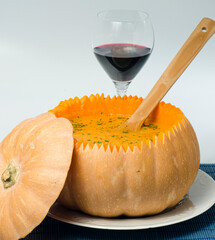 A large pumpkin filled with pumpkin cream, with a wooden spoon.