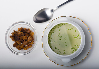 Ceramic soup tureen with consomm&eacute;, accompanied by a plate of toasted bread.