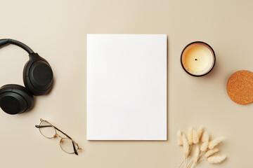 Blank paper, glasses, and wireless headphones on beige background