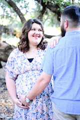 A pregnant woman smiling at her partner while holding her belly,