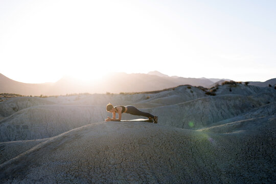 Woman training planks in the desert.
