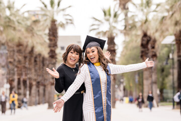 Excited mother and graduate daughter on graduation day with palm