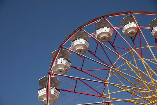 Ferris wheel against a clear blue sky at an amusement park.