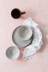 Stoneware plates with mug and linen on a pink table